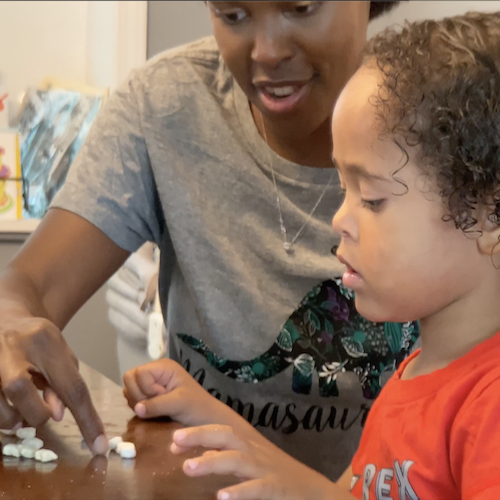 A special needs BuildUp coordinator helping a child with Maths by using small blocks